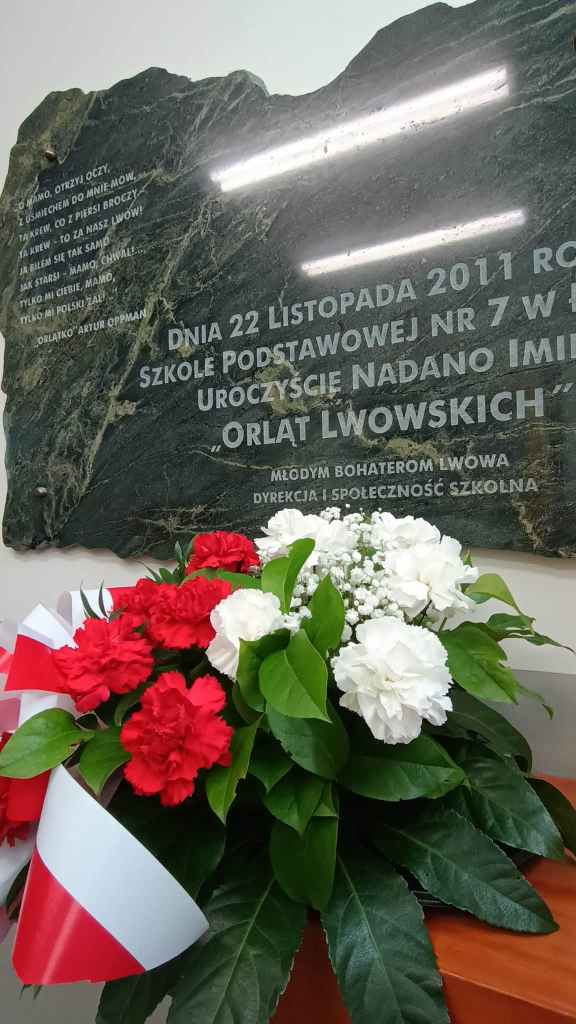 Kwiaty pod tablicą upamiętniającą nadanie imienia szkole