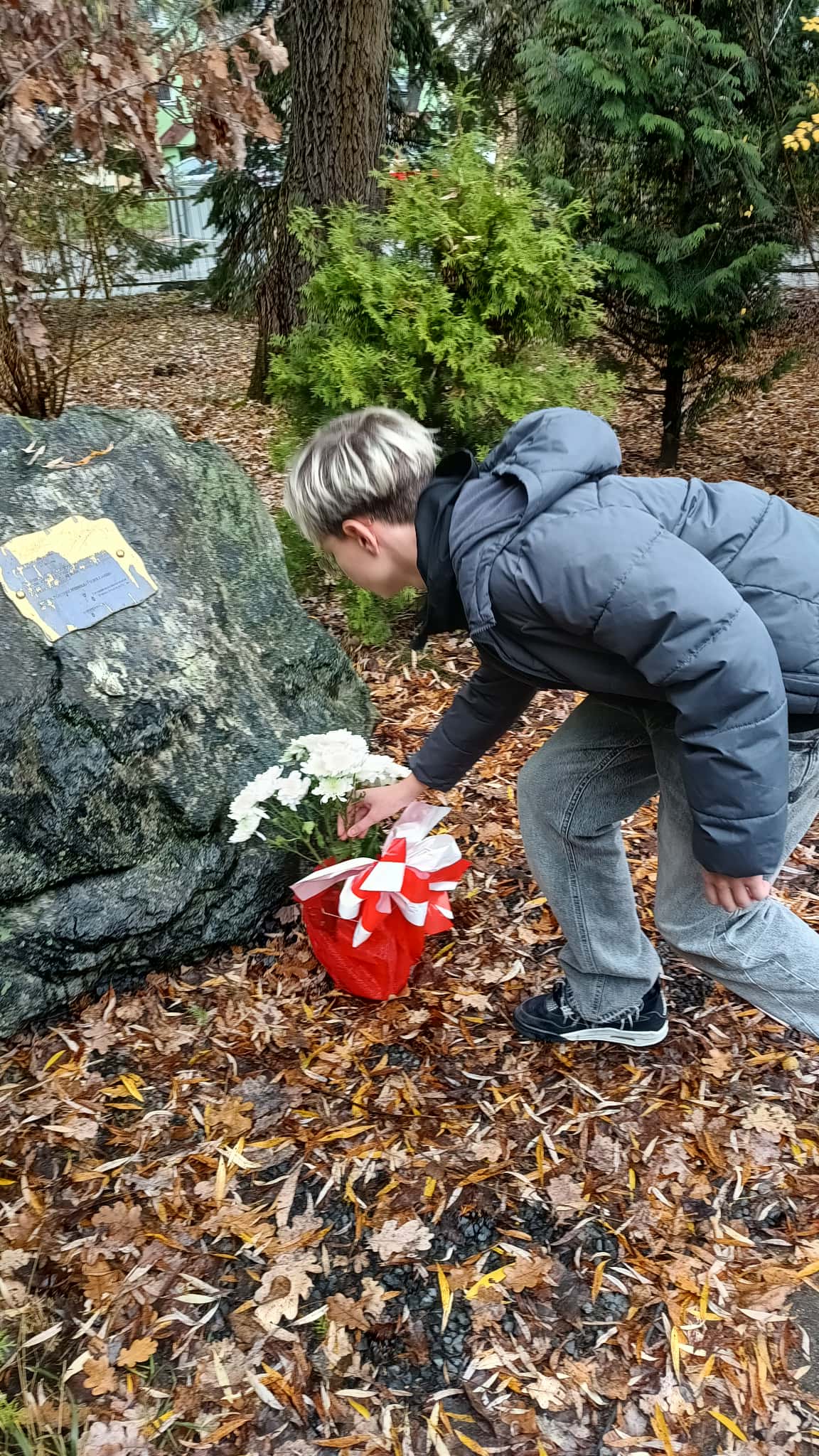Uczeń składa kwiaty pod pomnikiem
