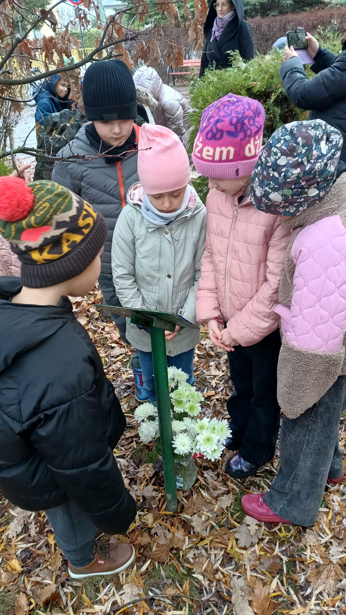 Dzieci czytają tabliczkę z napisami przy Dębie Pamięci