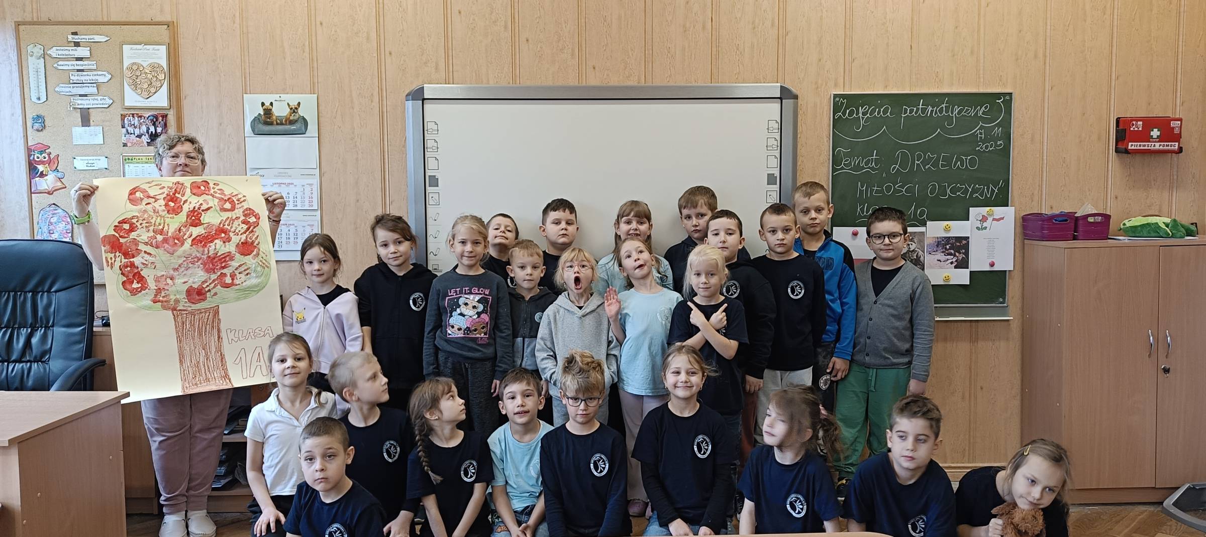 Uczniowie klasy 1a z plakatem odciśniętych dłoni w kolorze biało czerwonym