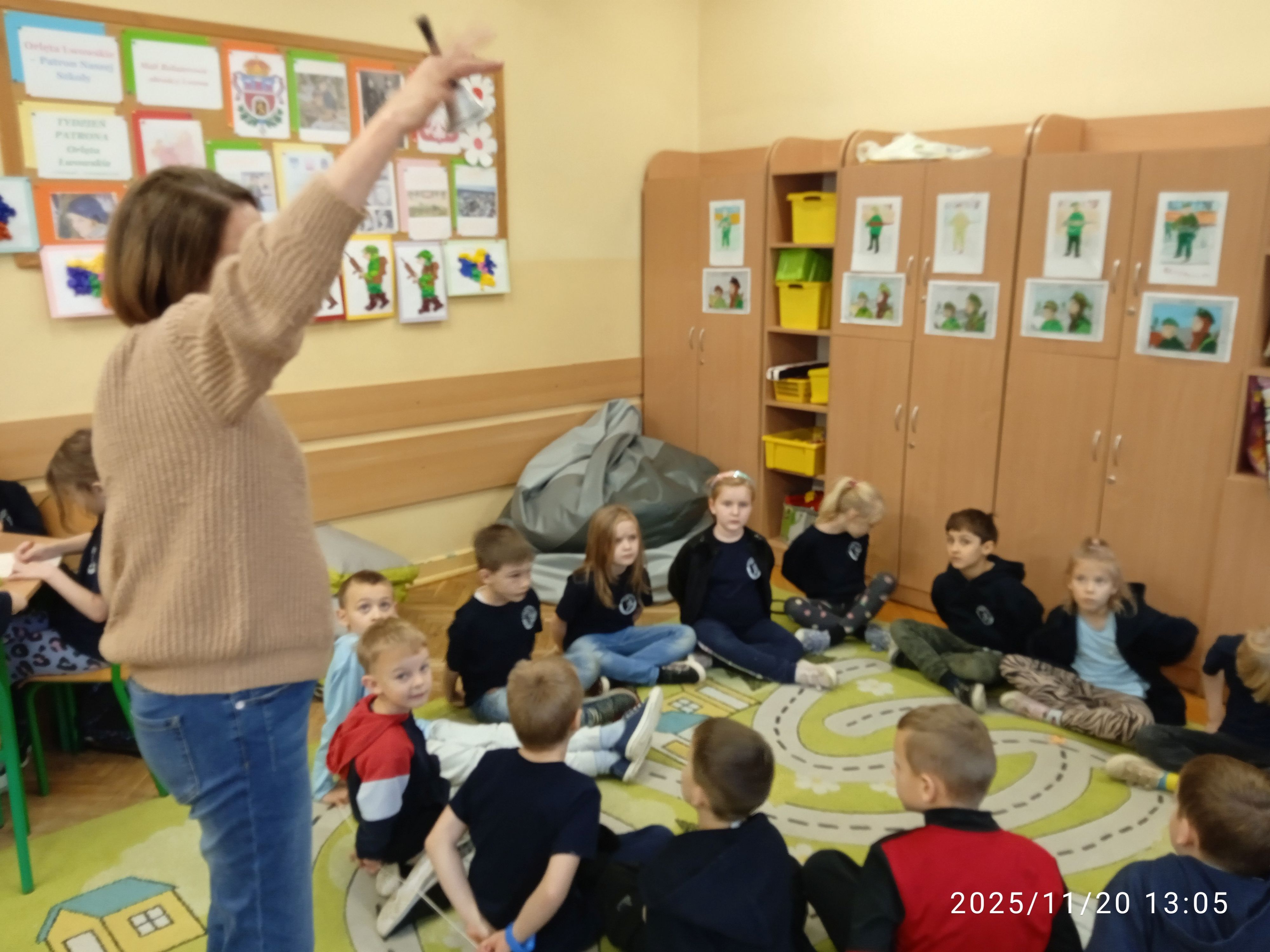 Uczniowie siedzą w kole i słuchają nauczyciela