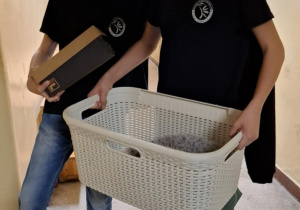 Uczniowie z stoją z koszem