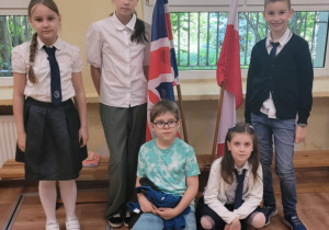 Uczniowie stoją przy flagach
