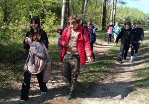 Uczniowie idą leśną ścieżką