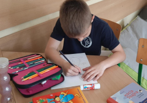 Uczeń wykonuje pracę plastyczna przy stoliku
