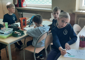 Uczniowie pracują przy stolikach w grupie