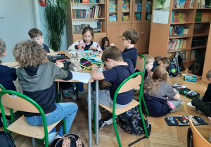 Dzieci współpracują ze sobą kolorując pracę plastyczna