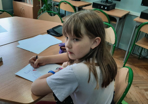 Uczennica rysuje portret przyjaciółki kredkami i mazakami