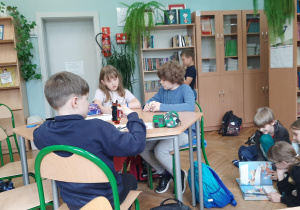 Uczniowie rysują przy stoliku portret swoich przyjaciół