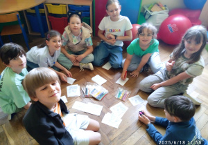 Uczniowie siedzą na podłodze