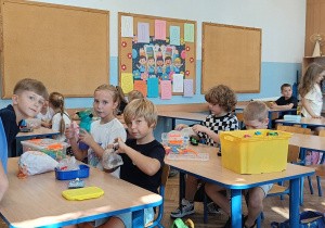 Uczniowie wspólnie wykonują zabawy przy stolikach jako przykład bycia dobrym w zabawie