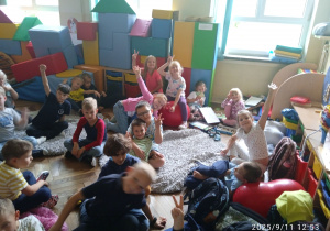 Uczniowie siedzą na dywanie w sali
