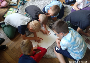 Uczniowie tworzą pracę na dywanie