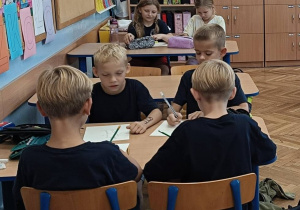 Dzieci pracują przy stolikach wykonując zadania praktyczna