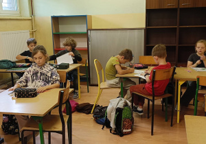 Dzieci pracują przy stolikach wykonując zadanie plastyczne