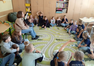 Uczniowie siedzą na dywanie