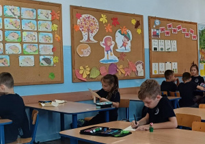 Uczniowie pracują w ławkach wykonując pracę plastyczną o jesieni