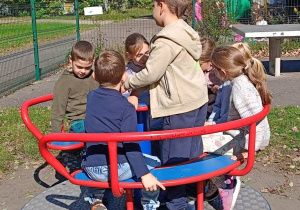 Uczniowie klasy I wspólnie bawią się na karuzeli integrując się w grupie