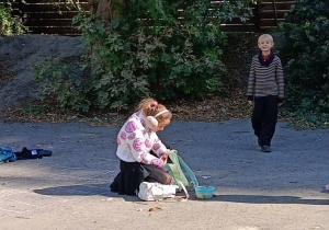 Uczniowie wspólnie rysują grę w klasy kredą na boisku szkolnym