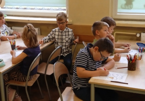 Uczniowie kolorują przy stolikach