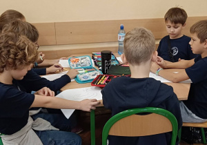 Dzieci pracują przy stoliku wykonując zadanie plastyczne
