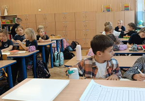 Dzieci współpracują ze sobą w parach przy stolikach podczas zajęć