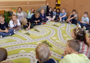 Dzieci siedzą w kole na dywanie
