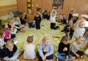 Uczniowie siedzą na dywanie