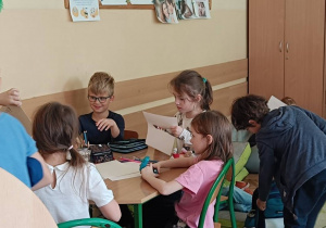 Dzieci wykonują pracę plastyczną przy stoliku