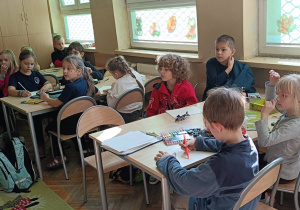 Uczniowie wykonują ćwiczenie plastyczne przy stolikach
