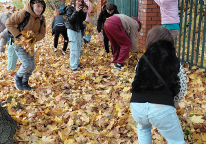 Uczniowie rzucają liśćmi