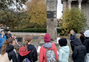 Uczniowie stoją przed pomnikiem