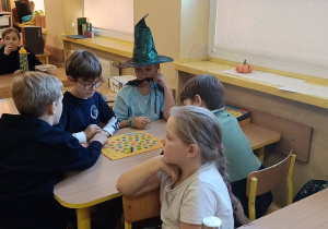 Dzieci wspólnie grają w zaproponowaną grę planszową ćwicząc współpracę w grupie