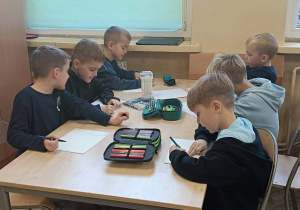 Dzieci tworzą w ławkach projekt plastyczny na konkurs o nie marnowaniu żywności