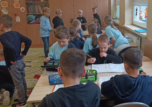 Uczniowie pracują w ławkach zastanawiają się nad hasłem konkursu