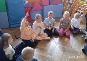 Uczniowie siedzą w kole na podłodze