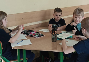 Dzieci pracują przy stoliku wykonując zadanie plastyczne