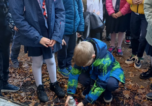 Uczeń stawia znicz pod pomnikiem