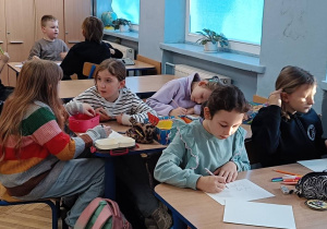 Dzieci wykonują w ławkach pracę plastyczną okulary dla niewidomych