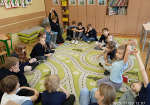 Uczniowie siedzą w kole na dywanie