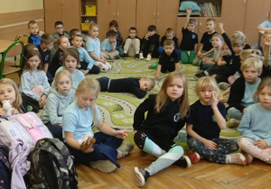 Uczniowie siedzą na dywanie