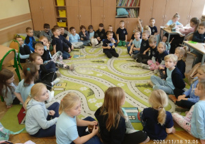 Uczniowie siedzą na dywanie w kole