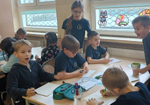 Uczniowie wykonują ćwiczenie praktyczne w grupie przy stoliku