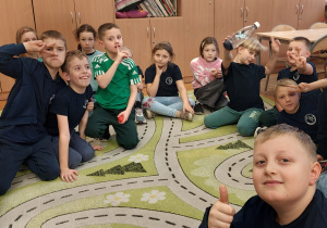 Uczniowie siedzą na dywanie