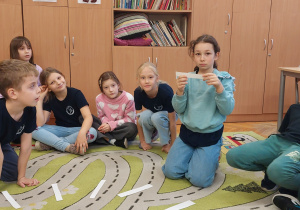 Uczniowie siedzą na dywanie