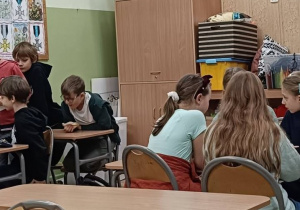 Dzieci współpracują podczas zajęć o wróżbach w ławkach