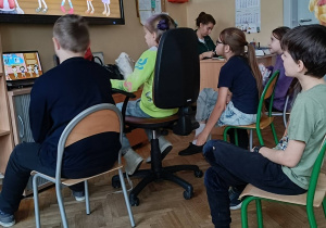 Uczniowie oglądają prezentację o święcie Andrzejek na tablicy multimedialnej
