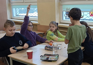 Uczniowie pracują w grupie przy stoliku wymyślają własne wróżby