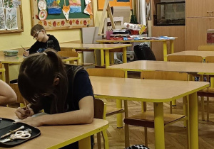 Dzieci wspólnie wykonują ćwiczenie z serdeczności wobec siebie w ławce