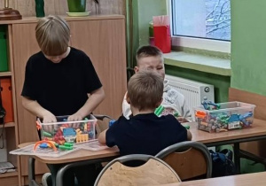 Uczniowie wspólnie układają klocki w ławce